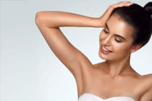 A woman posing with her arms raised, showing smooth underarms from laser hair removal